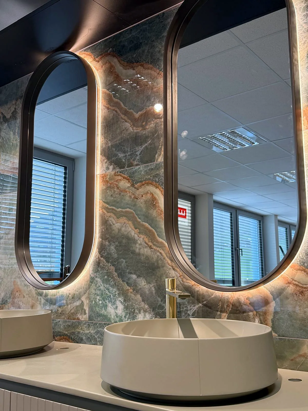Einblick in unsere Ausstellung in Zofingen: Waschtische, ovale Spiegel und eine Wand in Onyxoptik